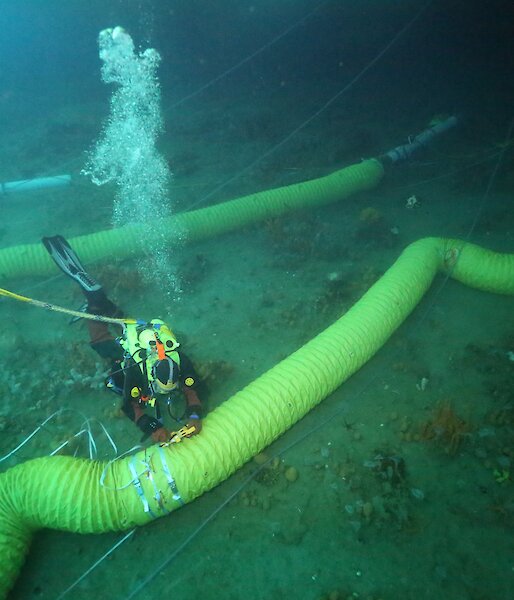 A diver working on a lowered duct. The inlet and the thrusters tubes which draw water into the experiment can be seen in the top right hand corner