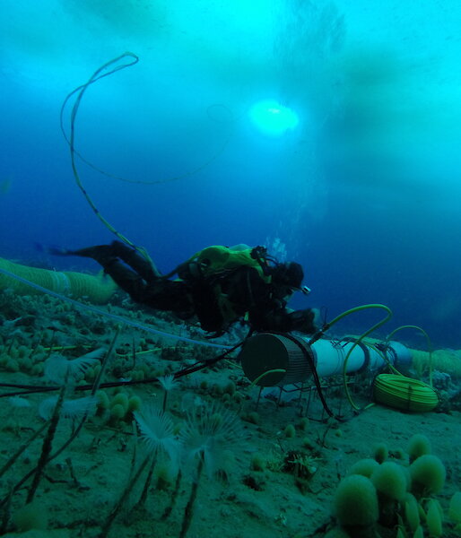 A diver inspects the thruster tubes that draw water into the system and through the chambers.