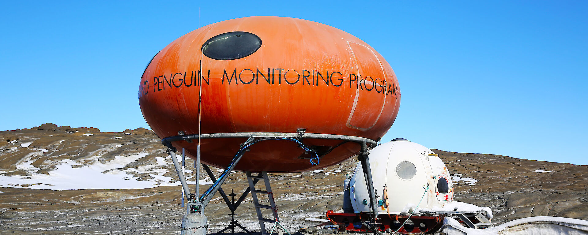 Orange googie field hut and white apple hut on Bechervaise Island