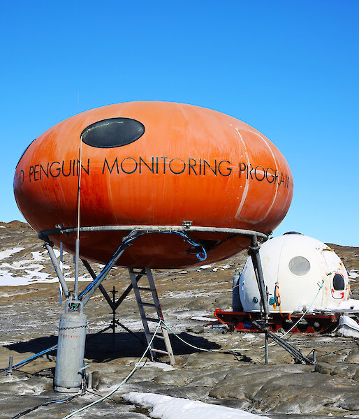 Orange googie field hut and white apple hut on Bechervaise Island