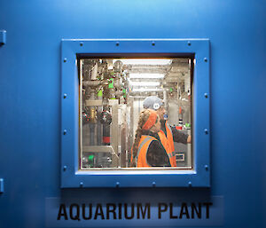 2 technicians, viewed through a window in a blue door labelled 'Aquarium Plant'.