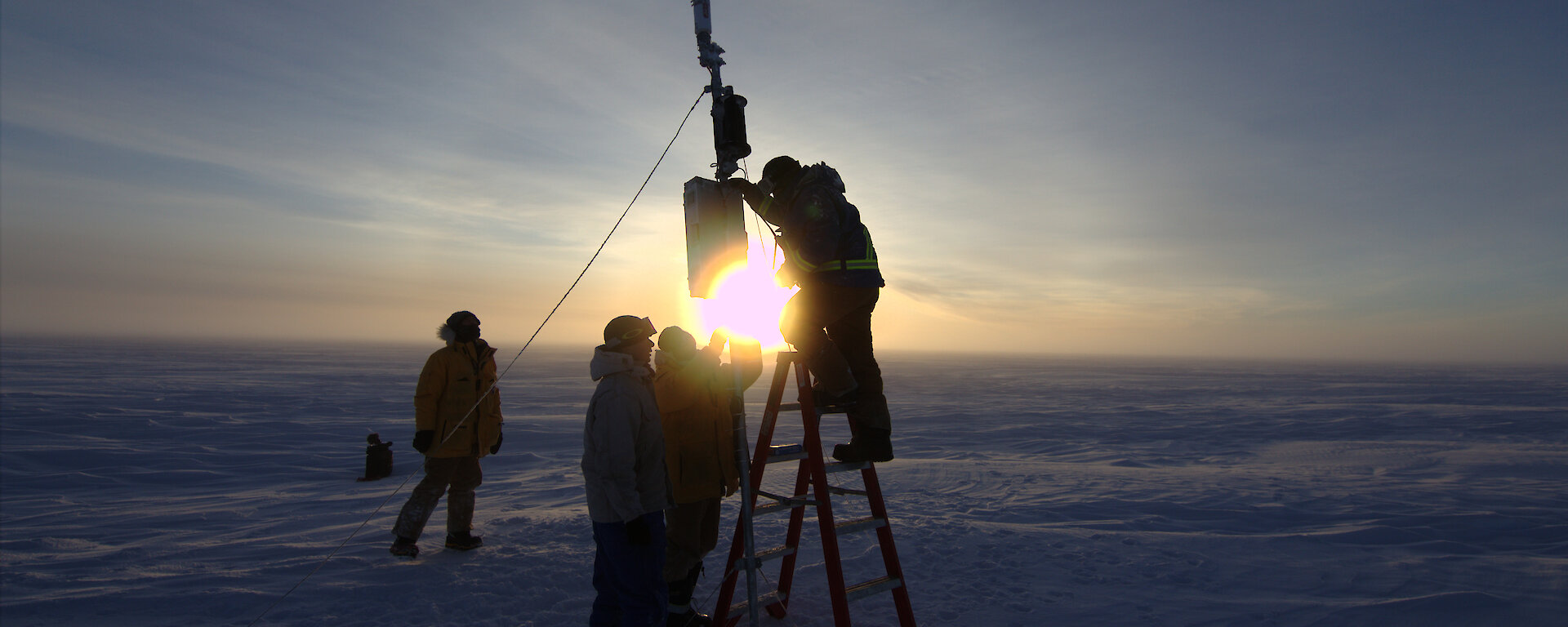 Four people installing equipment on the ice
