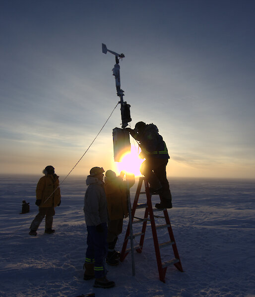 Four people installing equipment on the ice