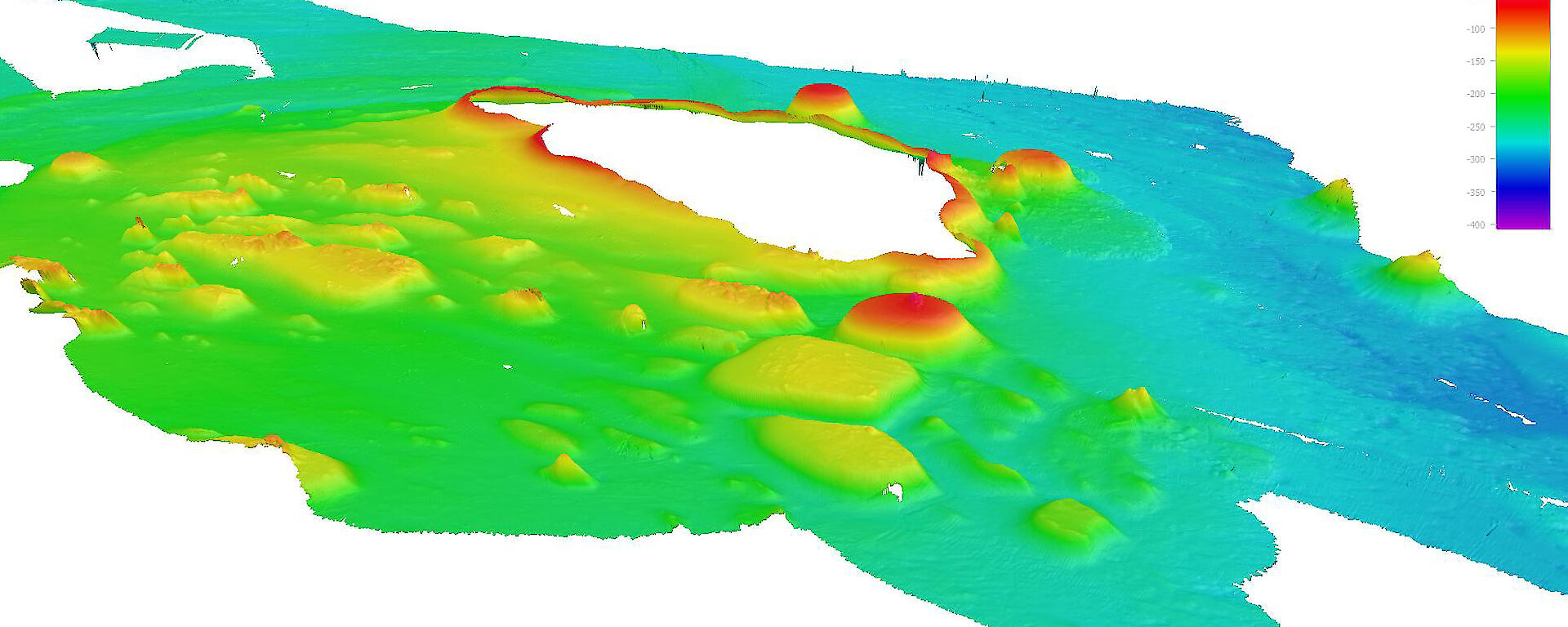 A three-dimensional view of presumed volcanic features – sea knolls – around the McDonald Islands (unmapped white area) produced from data collected by the ship’s seafloor mapping acoustic systems. Red and yellow colours indicate shallower features.