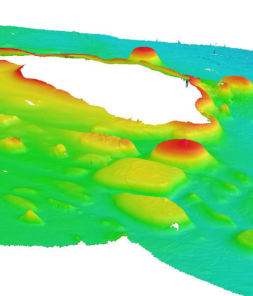 A three-dimensional view of presumed volcanic features – sea knolls – around the McDonald Islands (unmapped white area) produced from data collected by the ship’s seafloor mapping acoustic systems. Red and yellow colours indicate shallower features.