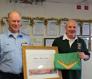 Captain Murray Doyle is presented with a weathered ANARE flag and certificate in honour of his last voyage to the Antarctic continent, by Casey station leader Pete Pedersen, in January 2016.