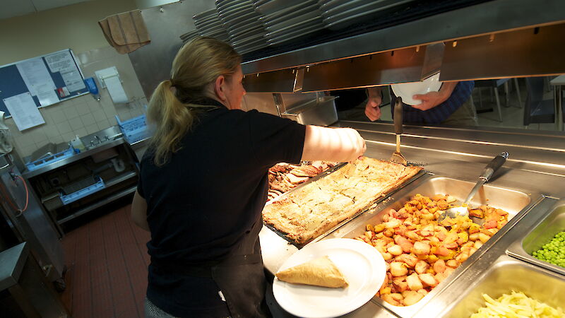 A chef at Casey filling the hot food servery.