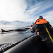 A whale researcher in a boat alongside a surfacing minke whale prepares to fire a satellite tag into the whale’s dorsal fin.