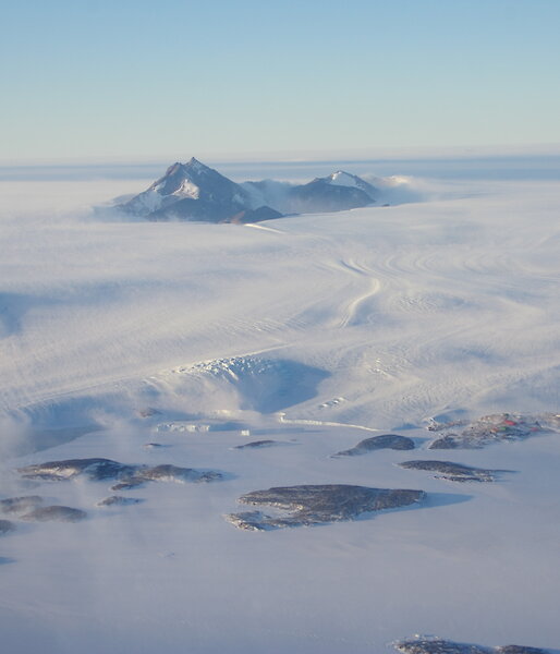 View of wind driven snow from a helicopter over rocky peaks near Mawson.