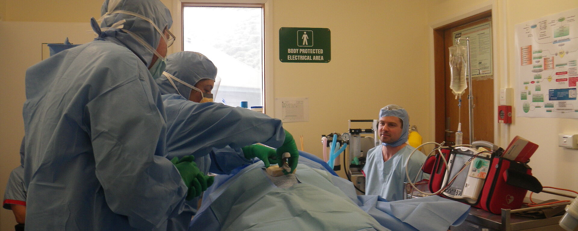 The doctor and lay-person surgical assistants conduct a mock operation on a ‘patient’ in the Macquarie Island station surgery.
