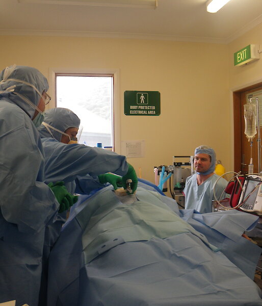 The doctor and lay-person surgical assistants conduct a mock operation on a ‘patient’ in the Macquarie Island station surgery.