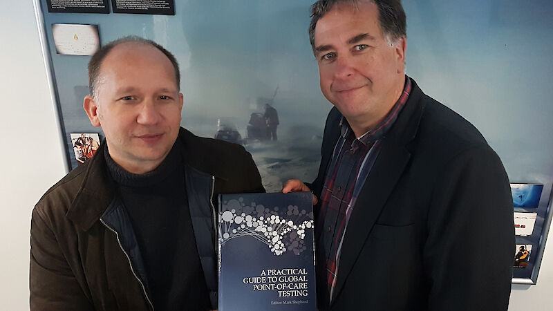 Dr Roland Watzl (left) and Dr Jeff Ayton with a copy of A Practical Guide to Global Point-of-Care Testing.