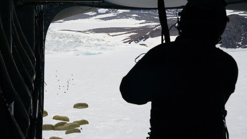 Drums of aviation fuel with parachutes are deployed from the back of a C17 aircraft.