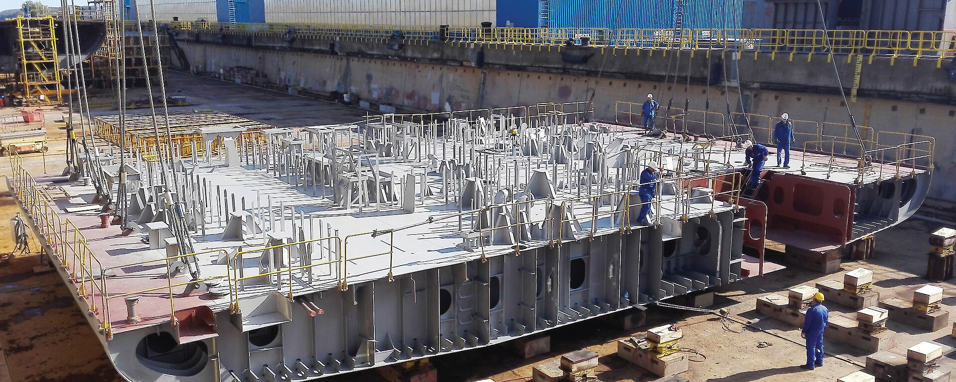 Placement of four conjoined blocks encompassing the deck forward of the engine room and the moon pool hull aperture, within the dry dock.