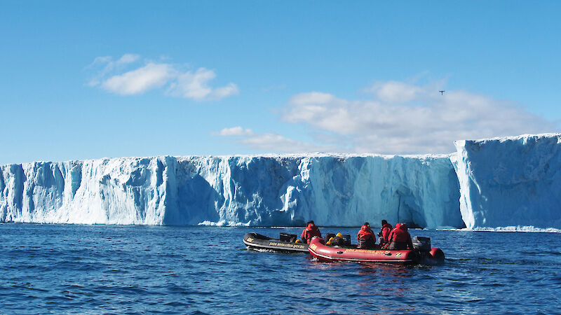 Two small boats with the Sørsdal Glacier in the background and a drone flying above the glacier.