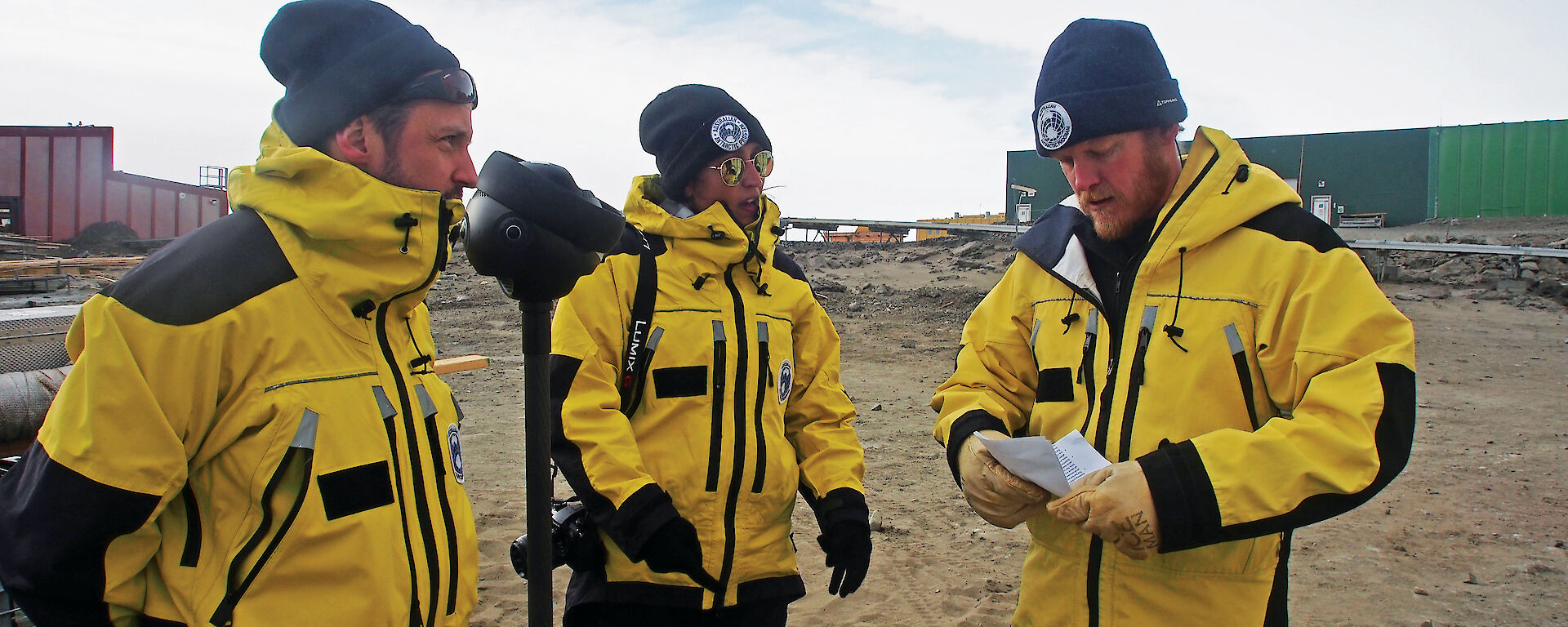 Phil Harper (left) and Briege Whitehead (centre) talk about station activities with Station Leader Robb Clifton, prior to filming. Wilson (wearing a protective lens sleeve) looks on.