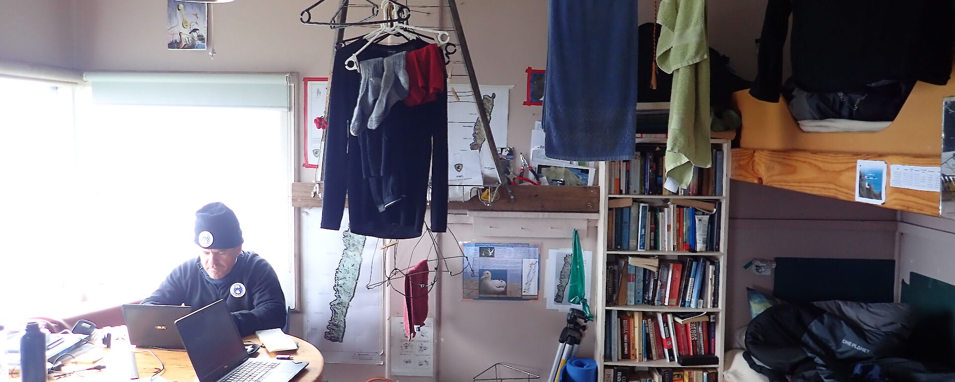 The inside of Hurd Point hut showing bunks, bookshelf and kitchen table, and clothes strung up to dry.