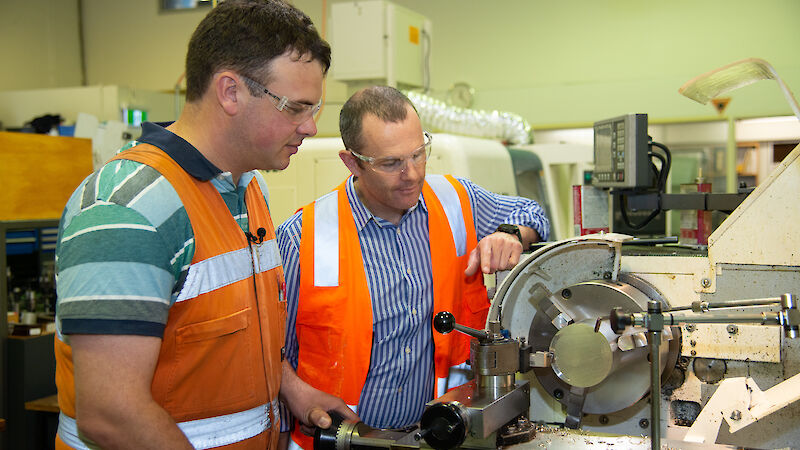 Two instrument technicians at a metal lathe.