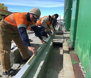 Three carpenters measuring cable ducting for the solar farm.