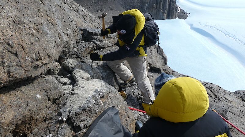 Field biologist, Marcus Salton, chisels a thick sample of very hard mumijo off rocks outside a nest cavity in the Masson Range near Mawson research station.