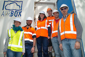 Six members of the AIRBOX team standing outside the shipping container.