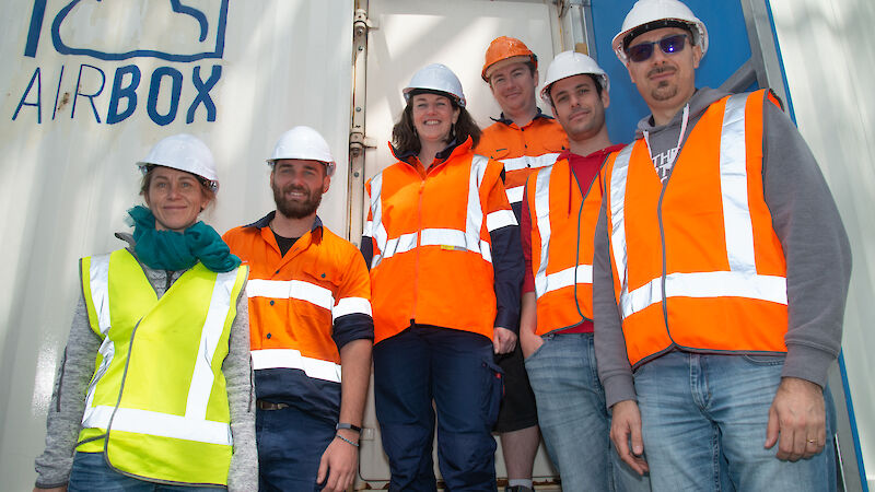 Six members of the AIRBOX team standing outside the shipping container.