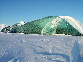 A jade iceberg rising above fast ice.