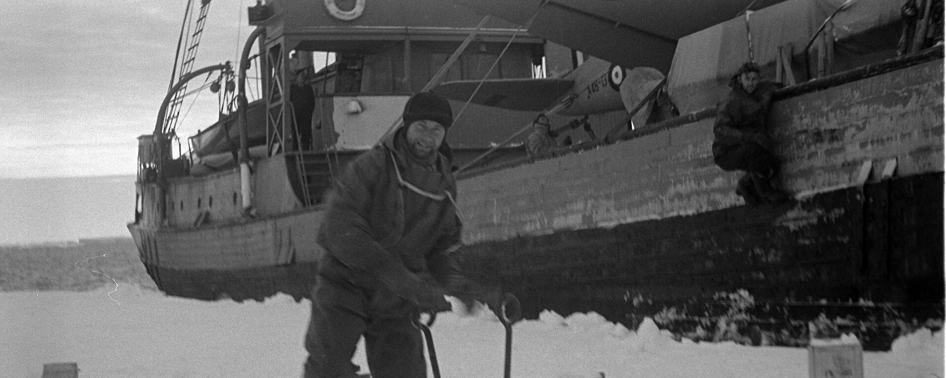 The Wyatt Earp moored beside sea ice with an expeditioner on the ice in front of the ship, collecting snow.