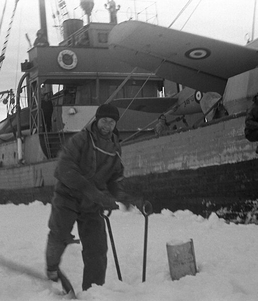 The Wyatt Earp moored beside sea ice with an expeditioner on the ice in front of the ship, collecting snow.