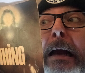 Close up of author with mock horror expression as he reads a book.
