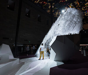 An artwork in a gallery space. Large shards of translucent material lit with a bright light reach from the floor to the ceiling of the gallery.