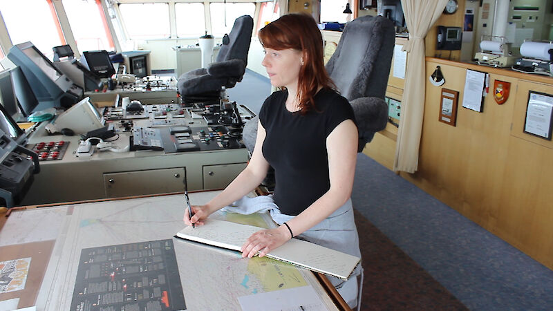 Favel Parrett on the Aurora Australis looking out the bow window while holding a notebook