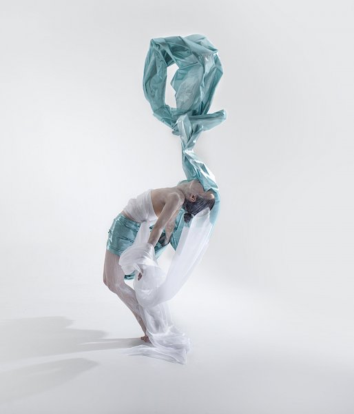 A dancer bends backwards while pretty fabric floats above her