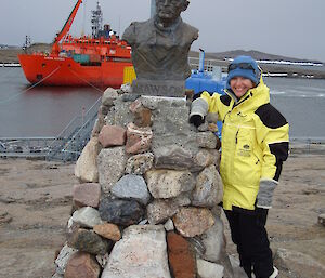 An expeditioner stands next to a statue of the explorer Mawson.