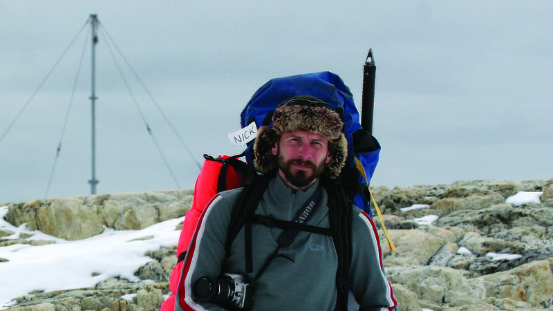 Nick Hutcheson at Wilkes with gear and backpack walking in a snowy landscape