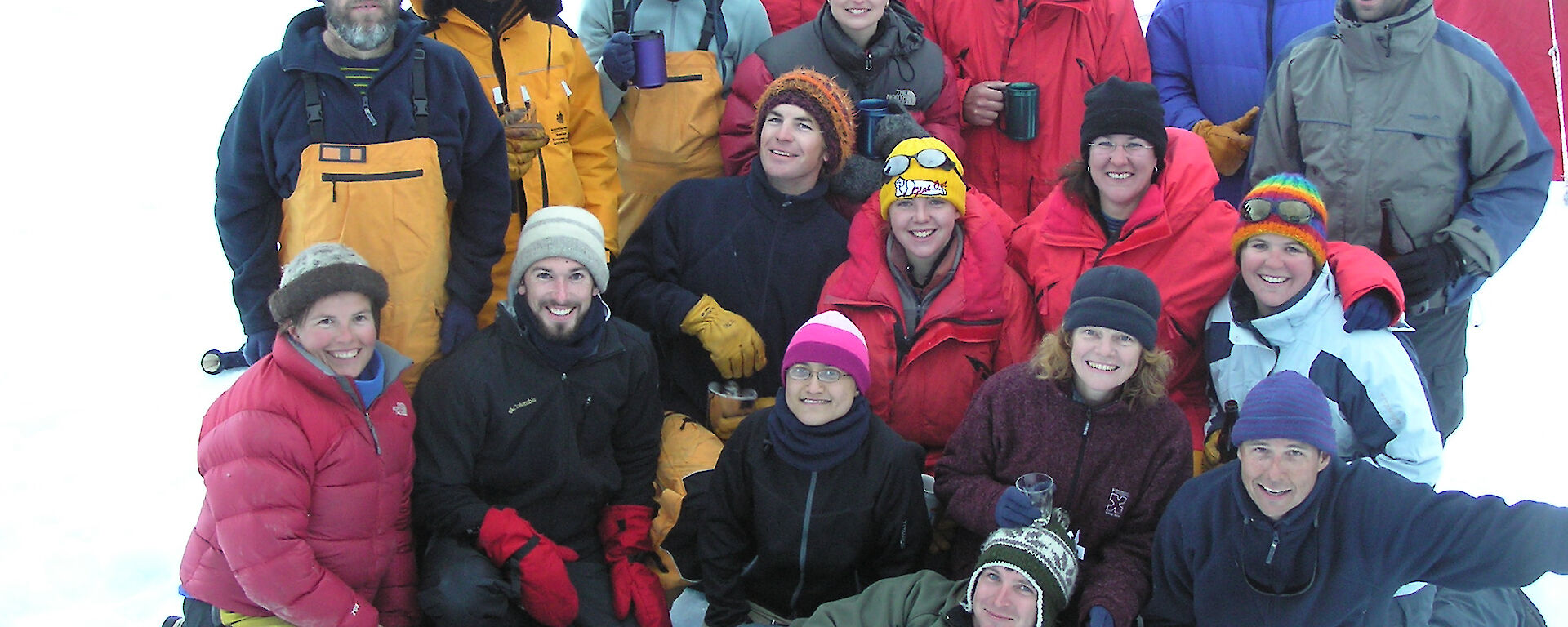 A group of expeditioners smile and pose for a photo on the snow.