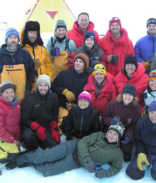 A group of expeditioners smile and pose for a photo on the snow.