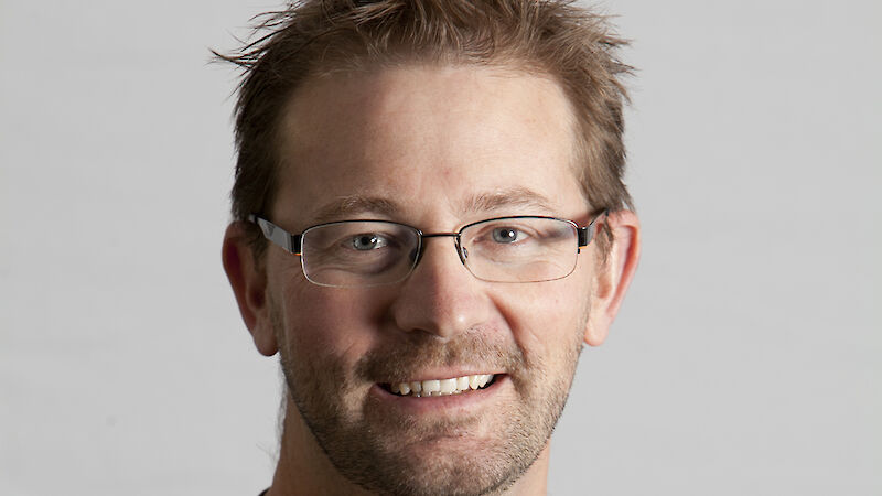 Man wearing glasses with sailboat masts in the background