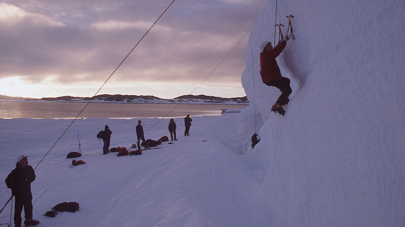 Woman climbs iceberg with ropes and an axe