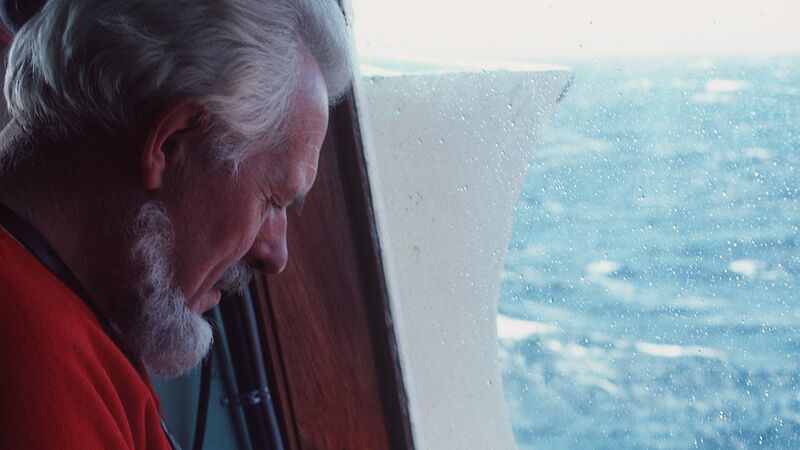 Stephen Walker sketching at a window on board a ship