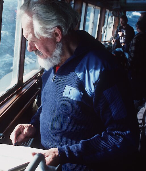 Stephen Walker sketching at a window on board a ship