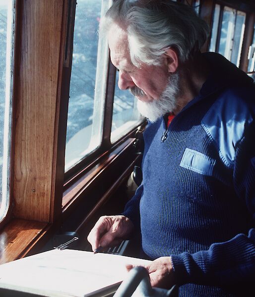 Stephen Walker sketching at a window on board a ship