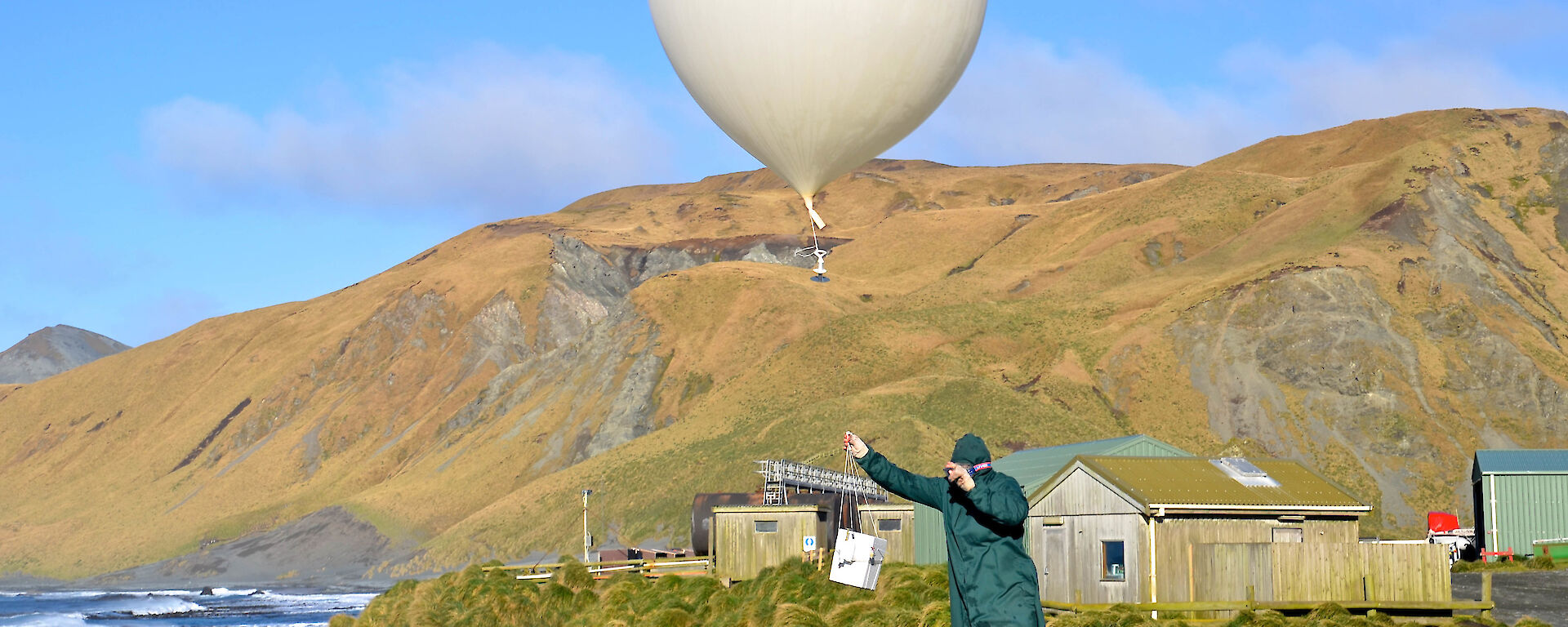 Expeditioner releasing meteorological balloon on clear day.