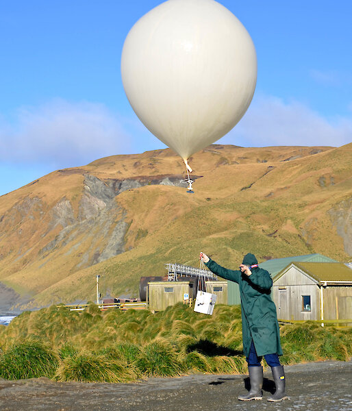 Expeditioner releasing meteorological balloon on clear day.