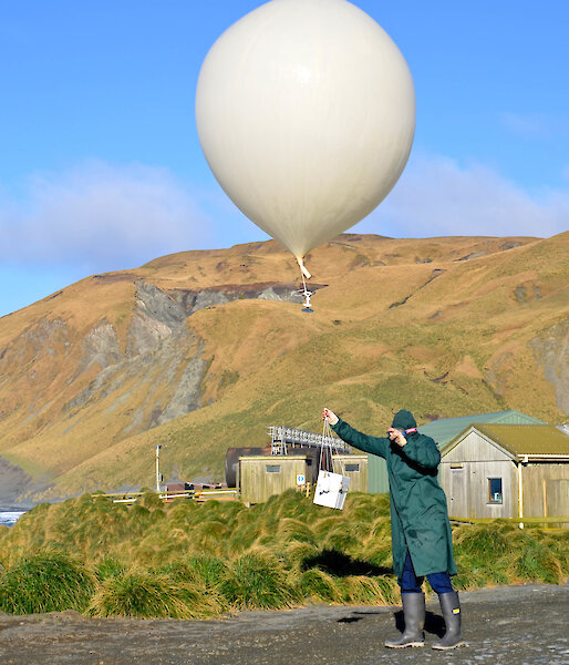 Expeditioner releasing meteorological balloon on clear day.
