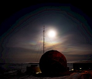 Shimmering rainbow-tinted clouds with polarised effect, over the silhouetted satellite dome