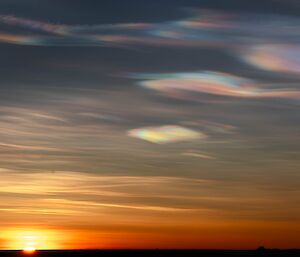 Iridescent clouds above an orange sunset.