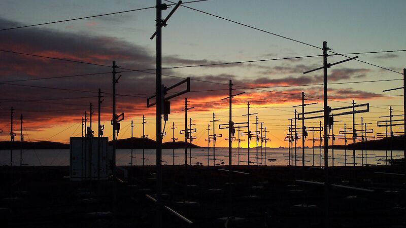 Orange sunset behind many antennas.