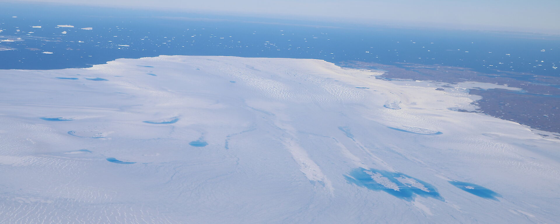 Aerial view of meltwater lakes with ocean beyond