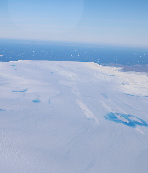 Aerial view of meltwater lakes with ocean beyond